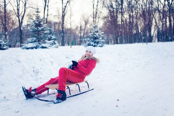 Усміхнена дівчина на санях у снігу взимку — стокове фото