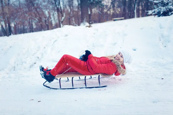 Ragazza sorridente su una slitta nella neve in inverno — Foto Stock