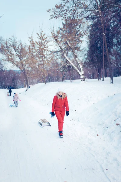 Jovem família correndo através da neve com trenó — Fotografia de Stock