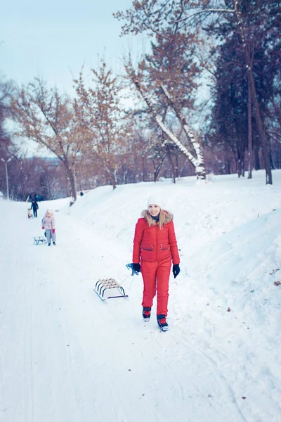 Giovane famiglia correre attraverso la neve con slitta — Foto Stock