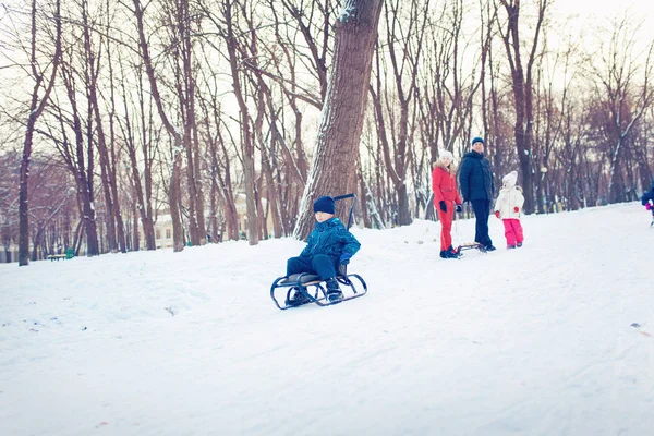 Giovane famiglia correre attraverso la neve con slitta — Foto Stock