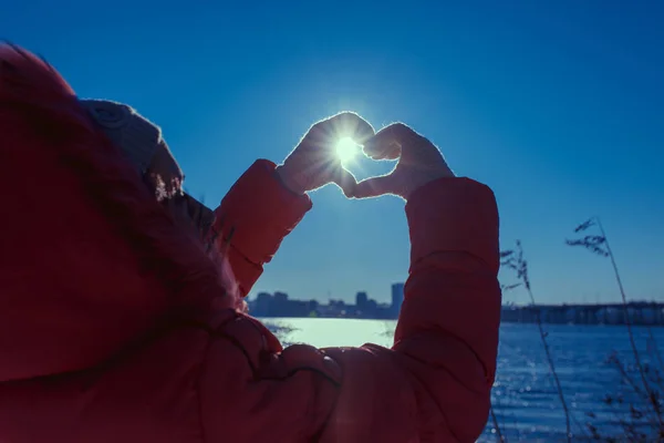 Mãos humanas gesticulando um sinal de amor sobre um fundo solar — Fotografia de Stock