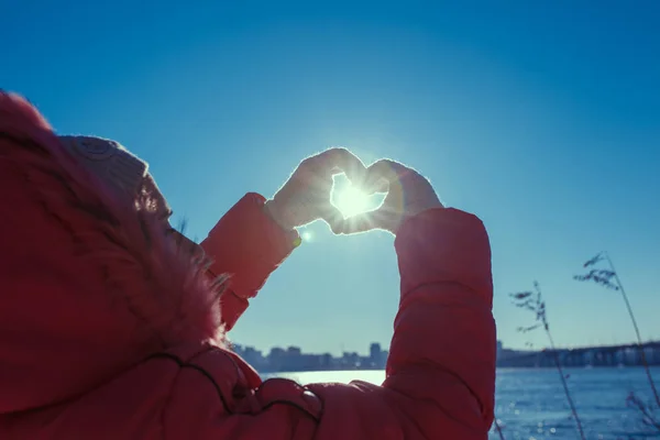 Manos humanas señalando un signo de amor sobre un fondo de sol — Foto de Stock