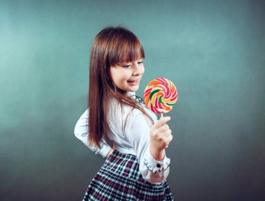Bir şeker winks holding neşeli güzel kız gösterir dil güler