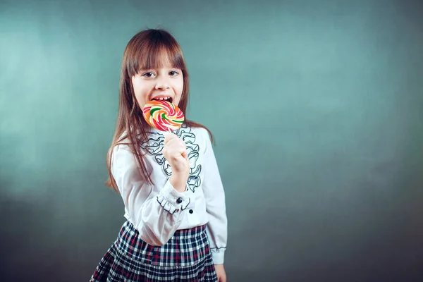 Веселая красивая девушка, держащая конфеты подмигивает смеется показывает язык — стоковое фото