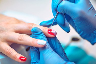 Usta kadın tırnaklarına oje sürüyor.