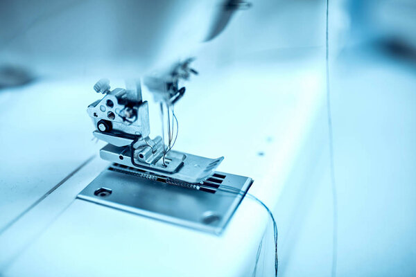 Швея вставляет нитку в старую швейную машину
