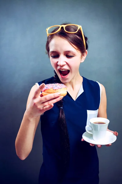Glada damen i T-shirt äta en munk och dricka kaffe — Stockfoto