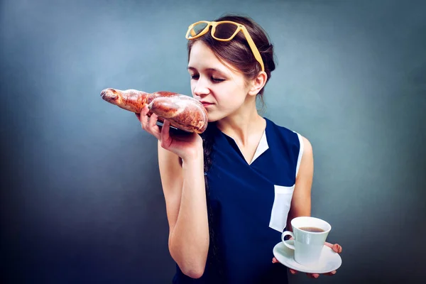 Glada damen i T-shirt äter en croissant och dricker kaffe — Stockfoto