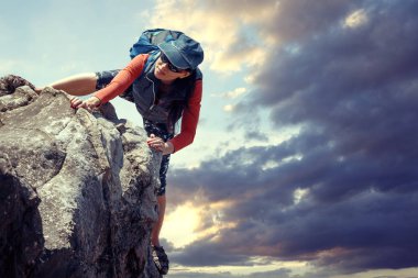 mutlu kadın açık havada doğa yürüyüşü sırasında bir kaya tırmanıyor. arka tasasız