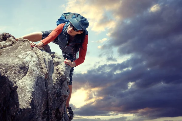 mutlu kadın açık havada doğa yürüyüşü sırasında bir kaya tırmanıyor. arka tasasız
