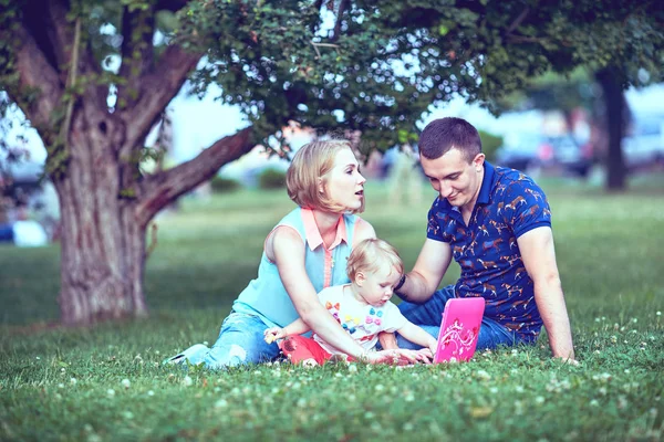 Happy family of three lying in the grass . — Stock Photo, Image