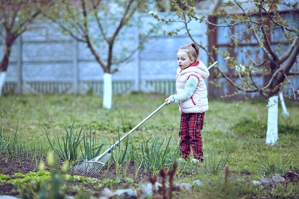 Raking in the Garden. Young girl play with rake. — Stock Photo, Image