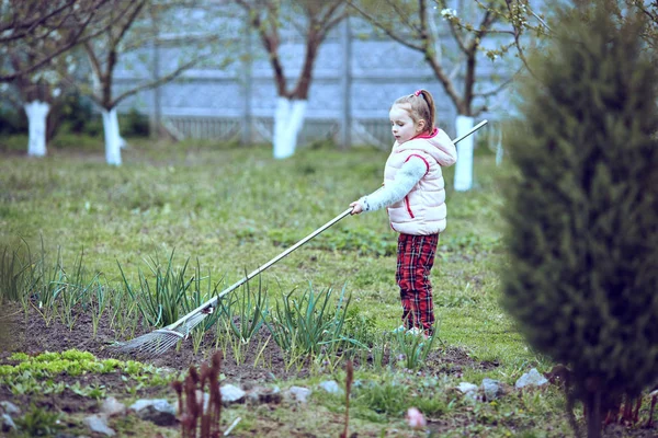 Harken in de tuin. Jong meisje spelen met hark. — Stockfoto
