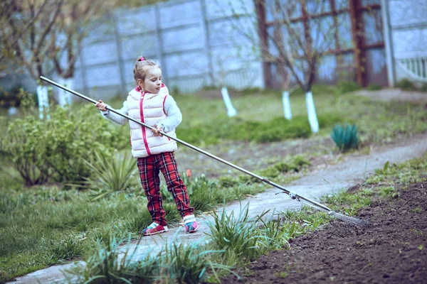 Raking in the Garden. Young girl play with rake. — Stock Photo, Image