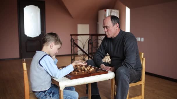 Knappe man spelen van dammen met zijn kleinzoon — Stockvideo