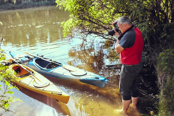Přírodní fotograf s kamerou v práci poblíž řeky — Stock fotografie