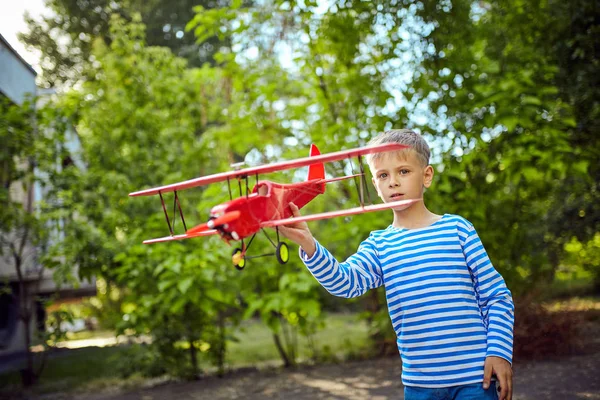 一个男孩一件背心在他手里拿着一架飞机 — 图库照片