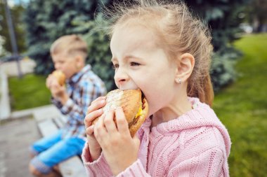 Çocuklar parkta hamburger yemek