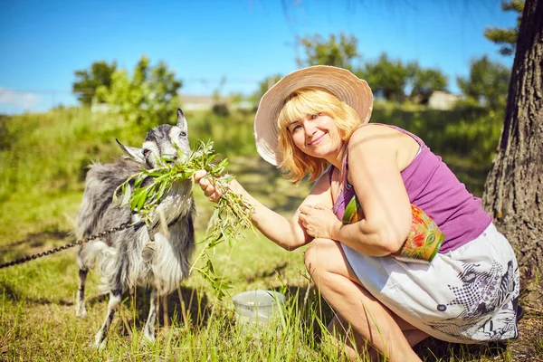 Village fille dans une prairie avec une chèvre — Photo