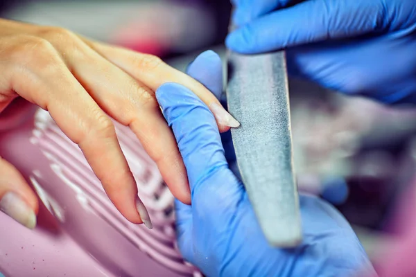 Meisje in handschoenen verwerkt nagels met een cutter frezen voor manicure — Stockfoto