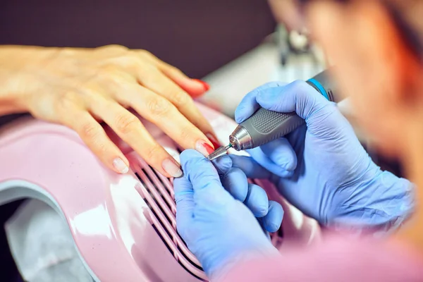 Meisje in handschoenen verwerkt nagels met een cutter frezen voor manicure — Stockfoto