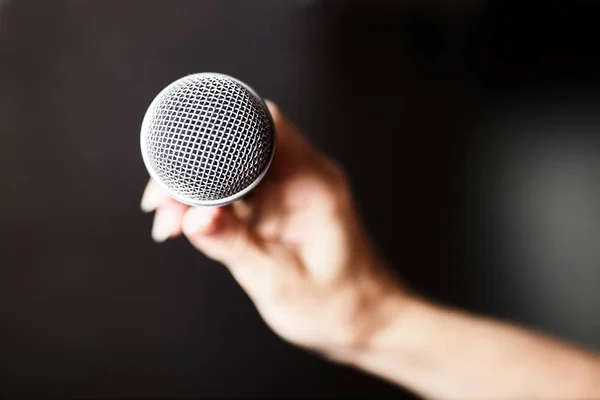 Female hand with microphone on background