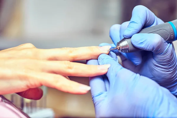 Meisje in handschoenen verwerkt nagels met een cutter frezen voor manicure — Stockfoto