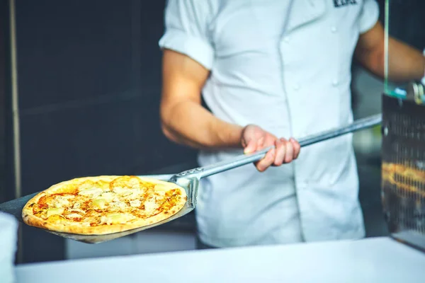 Kocken håller en stor pizza — Stockfoto