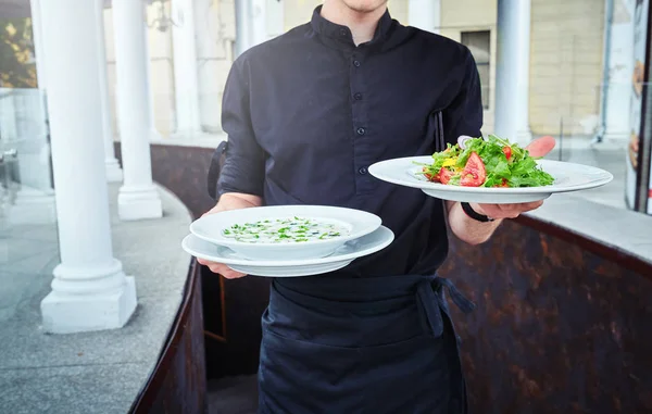 Camareros llevando platos con comida, en un restaurante . — Foto de Stock