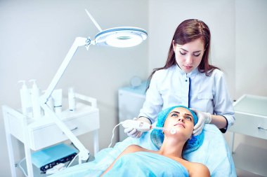 Güzellik uzmanı hastanın yüz için bakıyor