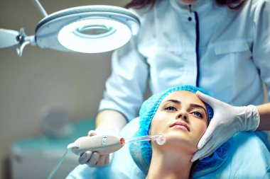 Güzellik uzmanı hastanın yüz için bakıyor
