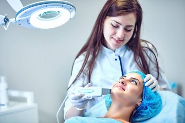 Güzellik uzmanı hastanın yüz için bakıyor