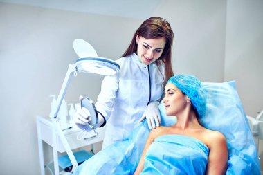 Güzellik uzmanı hastanın yüz için bakıyor