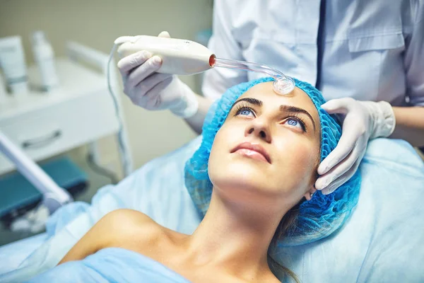 Kosmetolog är vårdande för patientens ansikte — Stockfoto