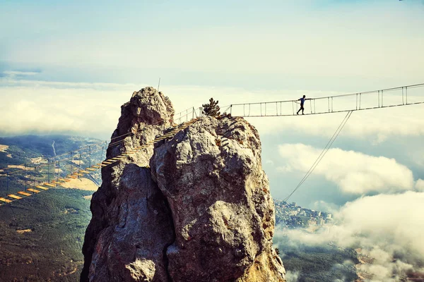 Mulher está andando ao longo de uma ponte suspensa sobre um abismo . — Fotografia de Stock