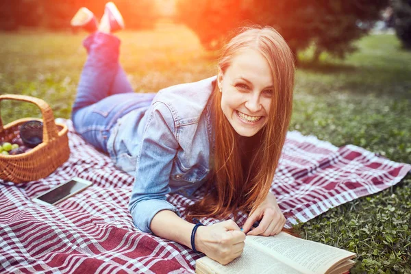 Menina leitura livro no parque no verão pôr do sol ligh — Fotografia de Stock