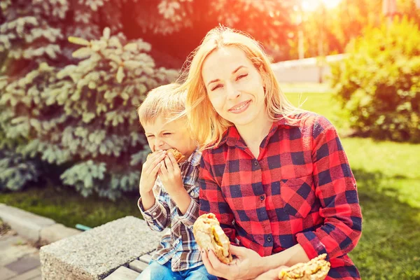 Maminka a děti jíst hamburger venku — Stock fotografie