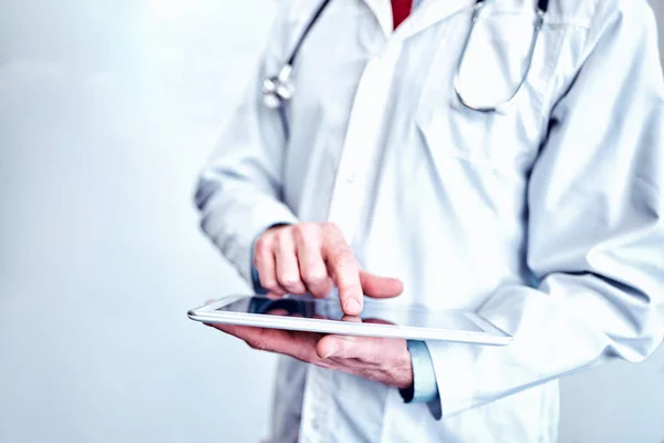 Doktor beyaz tıbbi paltolu bir tablet kullanma ve ızg gülümseyen