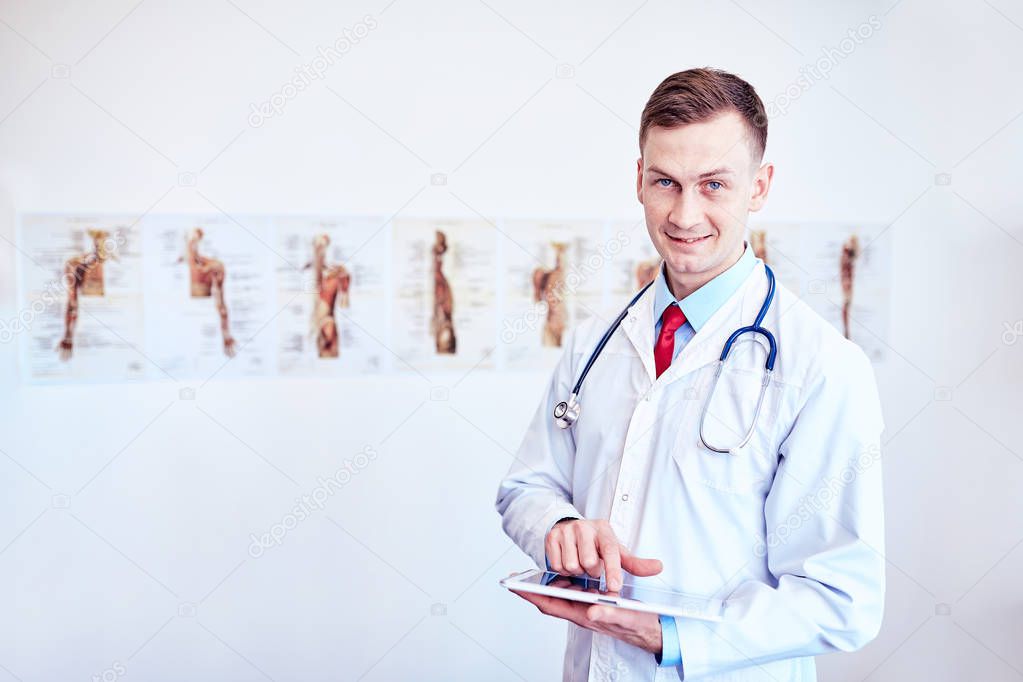doctor in white medical coat  is using a tablet and smiling whil