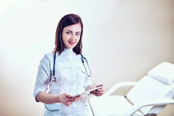 Doctor in de witte medische vacht is met behulp van een tablet en glimlachend gebruikswoord — Stockfoto