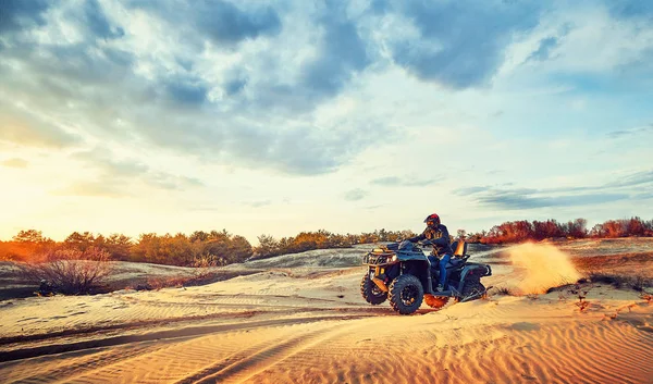 Підліток їде на квадроциклі в піщаних дюнах, роблячи поворот у піску — стокове фото