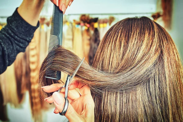 cropped image of hairdresser trimming ends of blonde hair