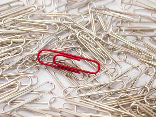 Red paper clip stand different from the crowd on white background