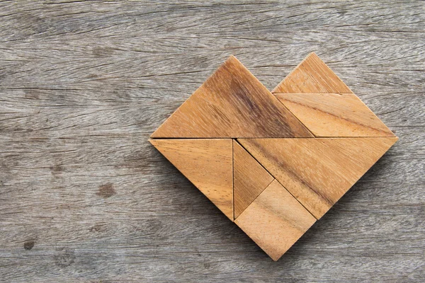 Tangram puzzle ve tvaru srdce na dřevěný stůl — Stock fotografie
