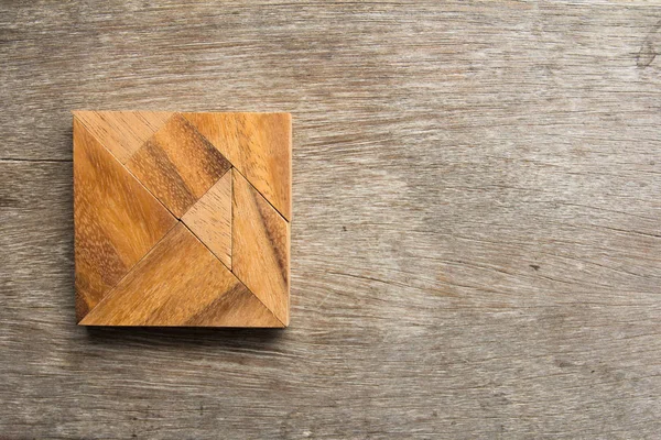 Tangram puzzle in square shape on wooden background