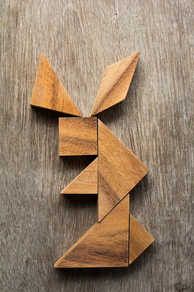 Ξύλινα tangram ως κουνέλι κάθεται σχήμα σε παλιό ξύλο φόντο — Φωτογραφία Αρχείου