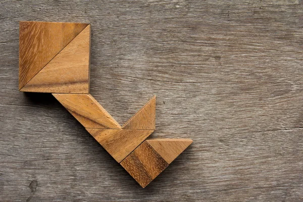 Wooden tangram as key shape on old wood background