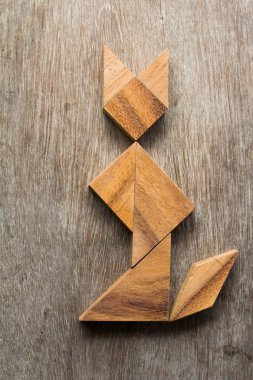 Şekil eski ahşap arka plan üzerinde oturan kedi olarak ahşap tangram