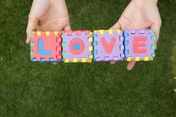 Puzzle wording love has hold on hand with green background